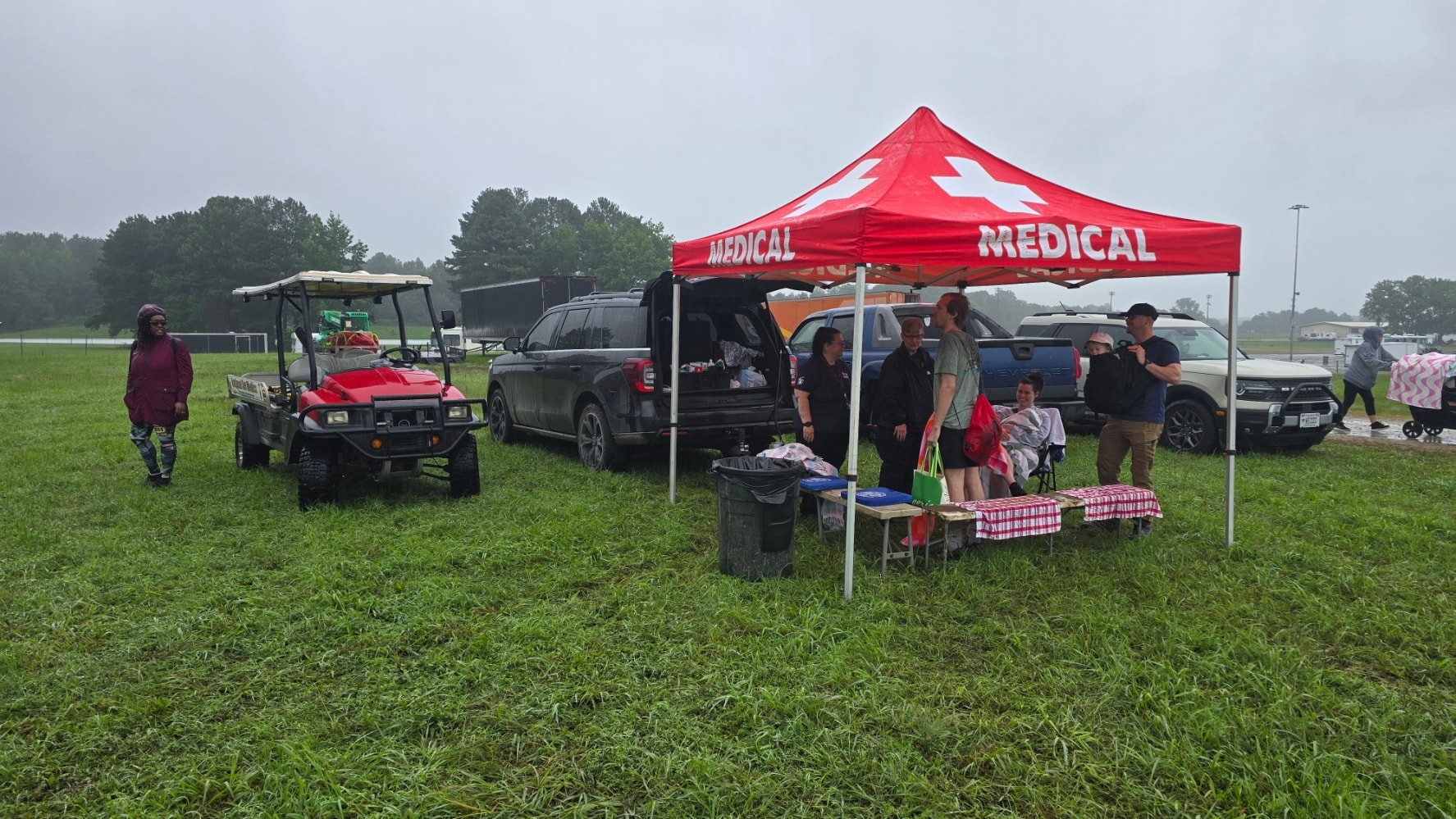 NSM red medical tent with crew and golf cart at a rainy outdoor event