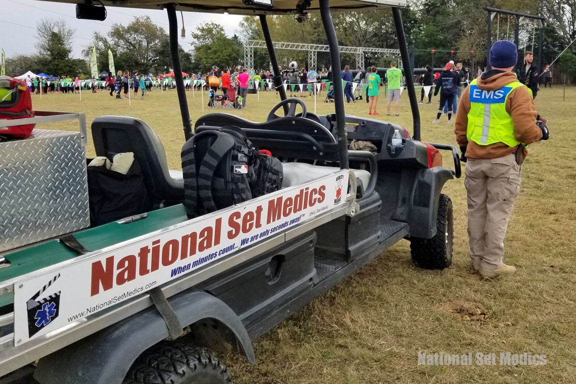 NSM EMS medic standing beside a branded National Set Medics cart at an outdoor event